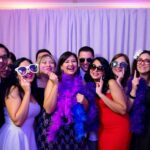 Invités souriants dans une cabine photo de mariage avec des accessoires.